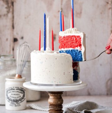 A red, white and blue cake with one slice being lifted up.