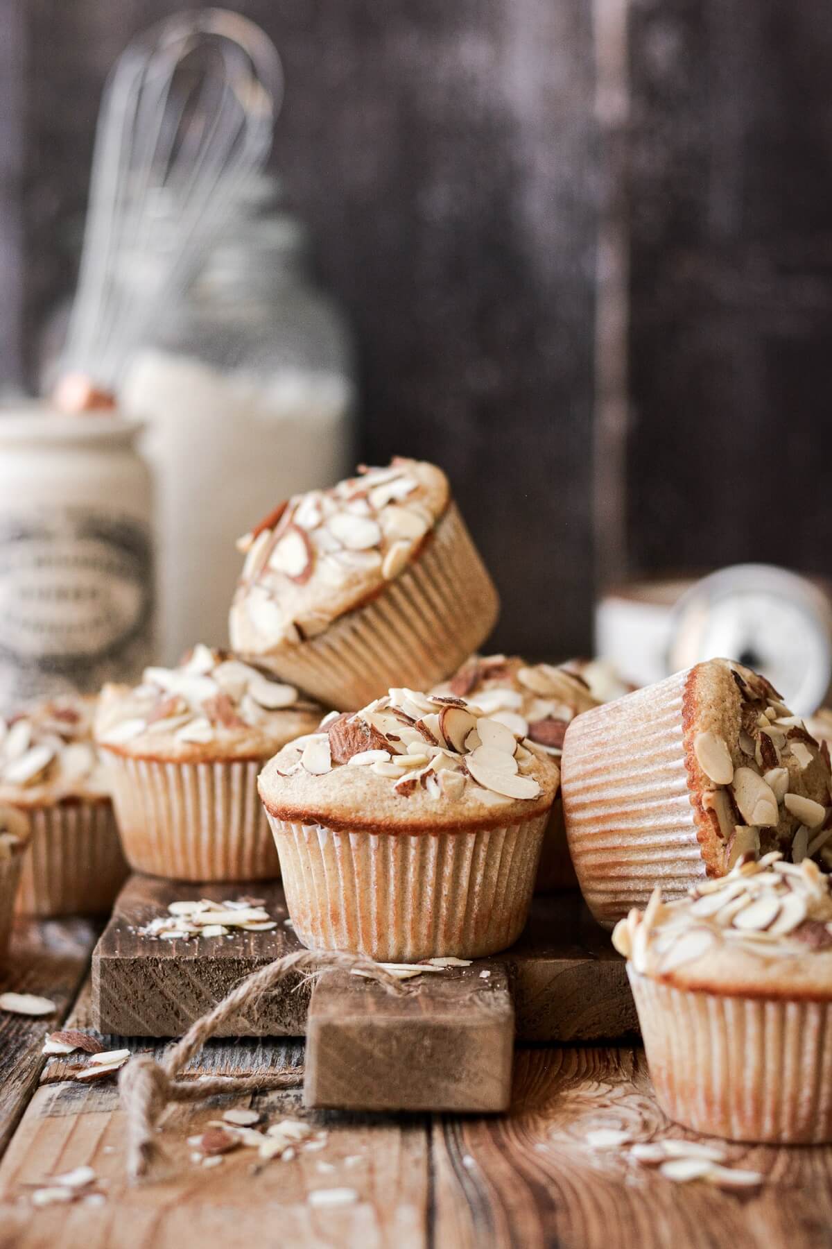 Almond muffins stacked on a wooden board.