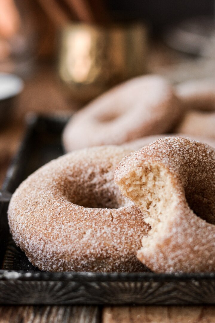 Cinnamon sugar whole wheat donuts, one with a bite taken.