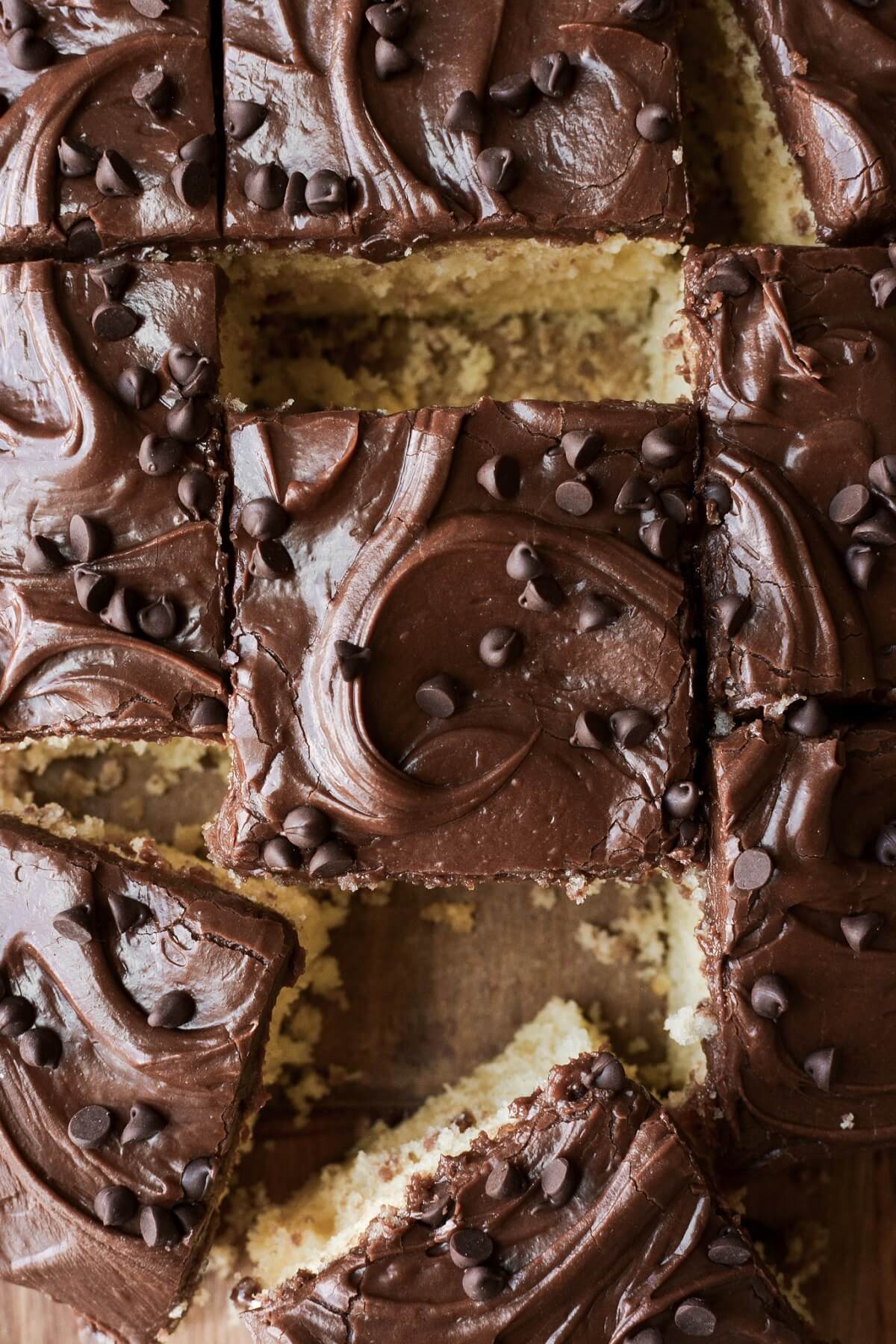 Squares of yellow birthday cake with chocolate frosting.