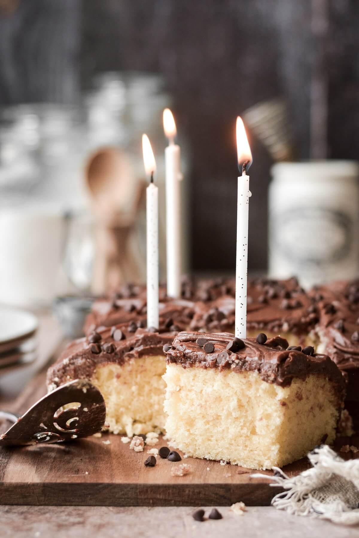 Pieces of yellow birthday cake with chocolate frosting, topped with birthday candles.