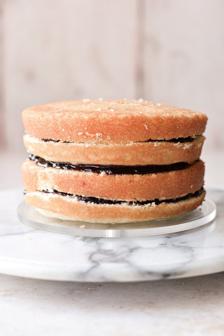 Four layers of vanilla cake stacked and filled with blueberry jam.