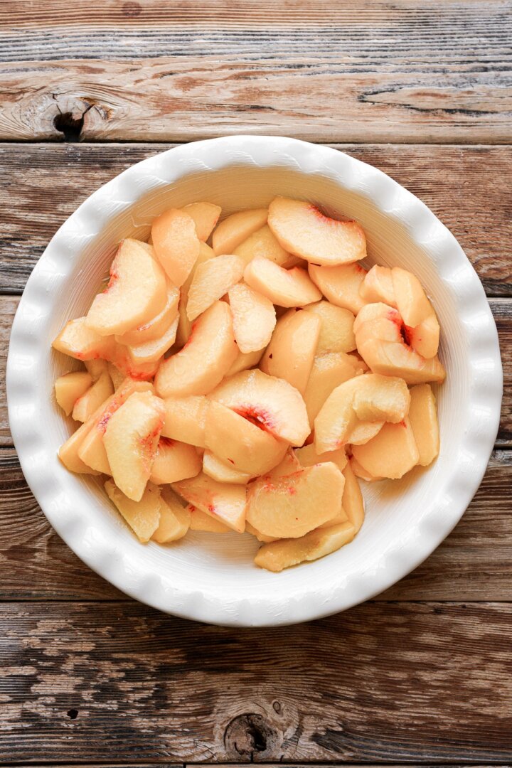 Sliced peaches in a pie pan.