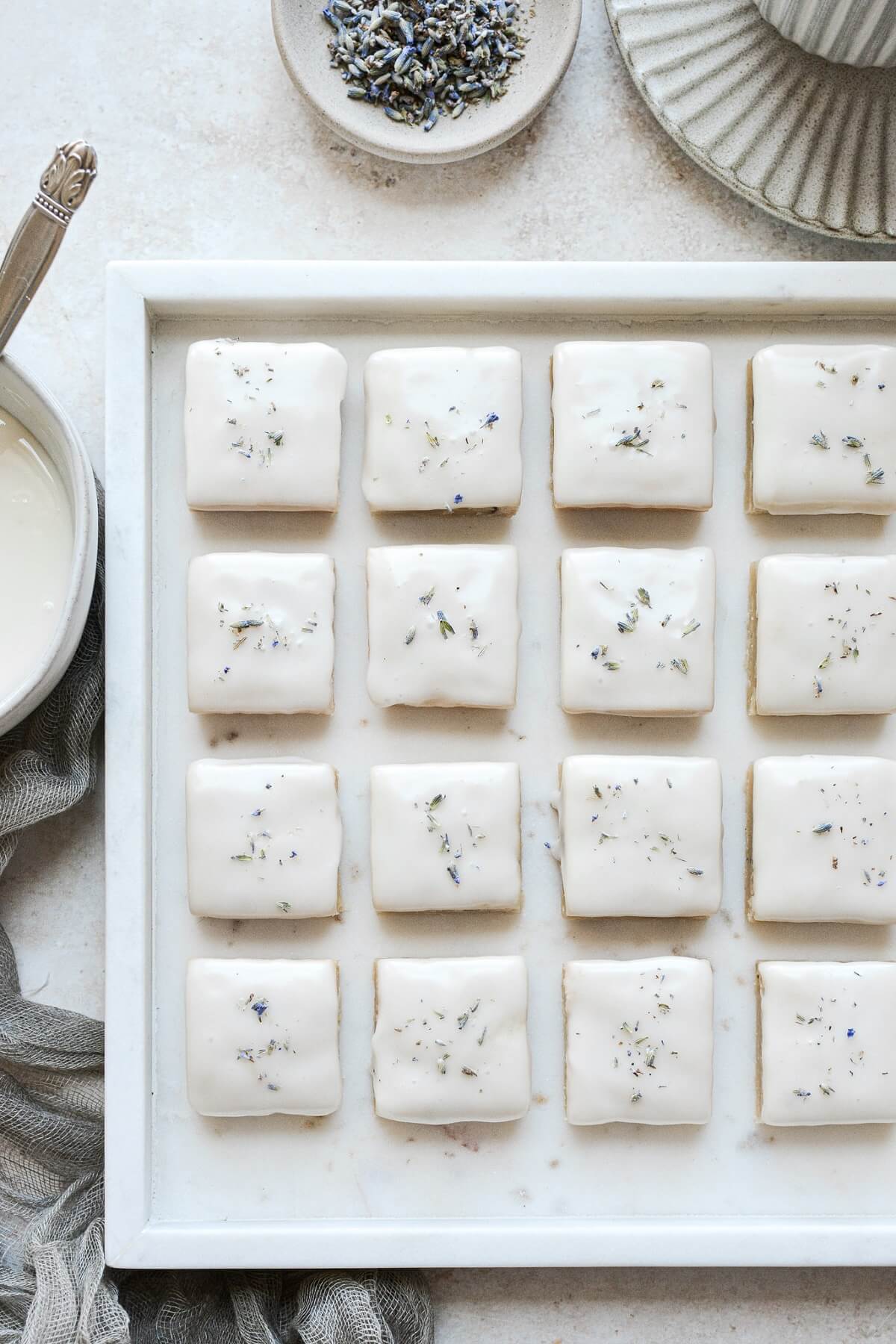 Iced lavender lemon shortbread cookies on a marble tray.
