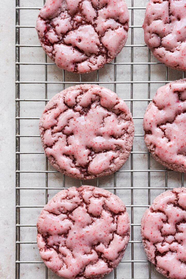 Iced strawberry cookies on a cooling rack.
