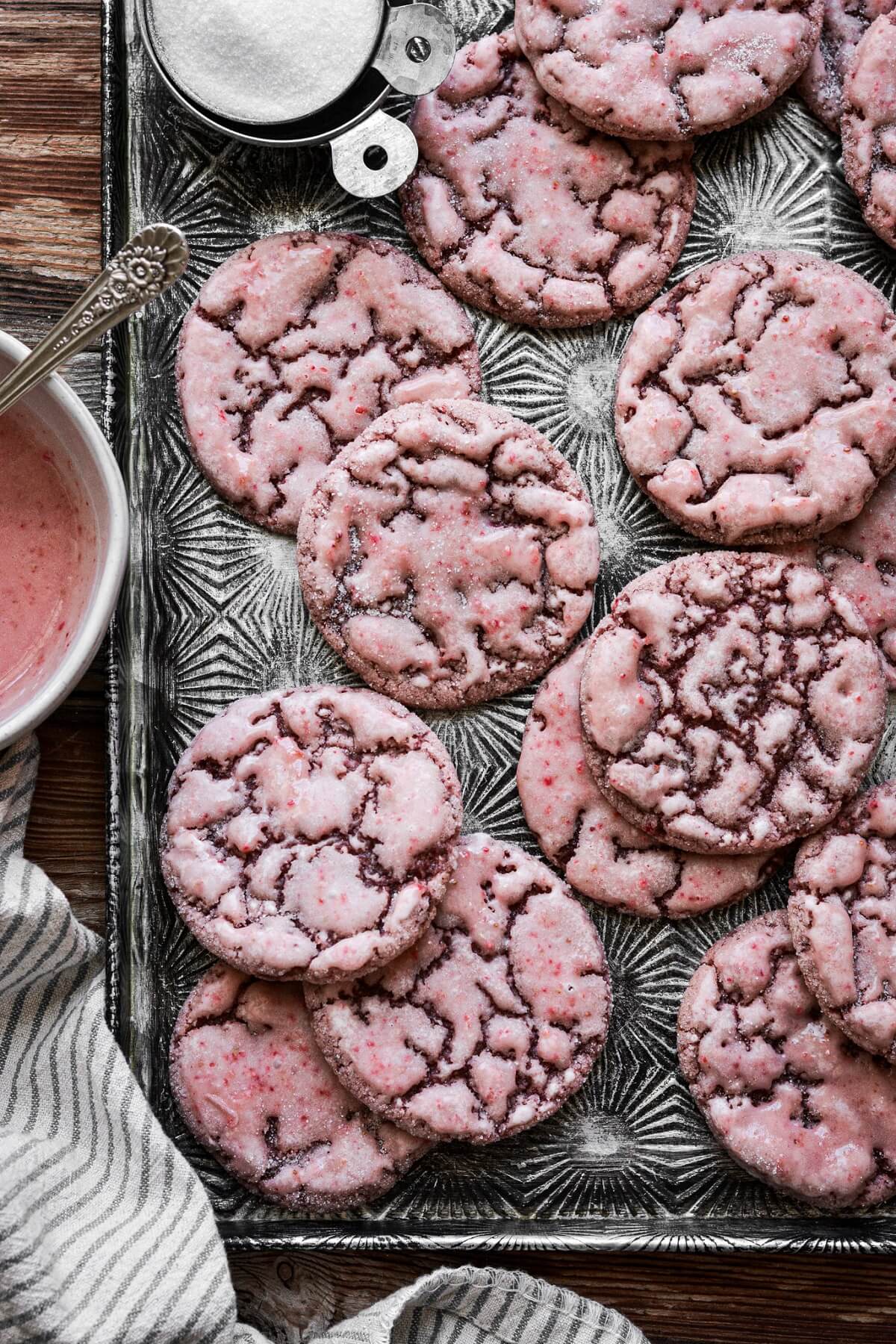 Iced strawberry sugar cookies on a vintage baking sheet.