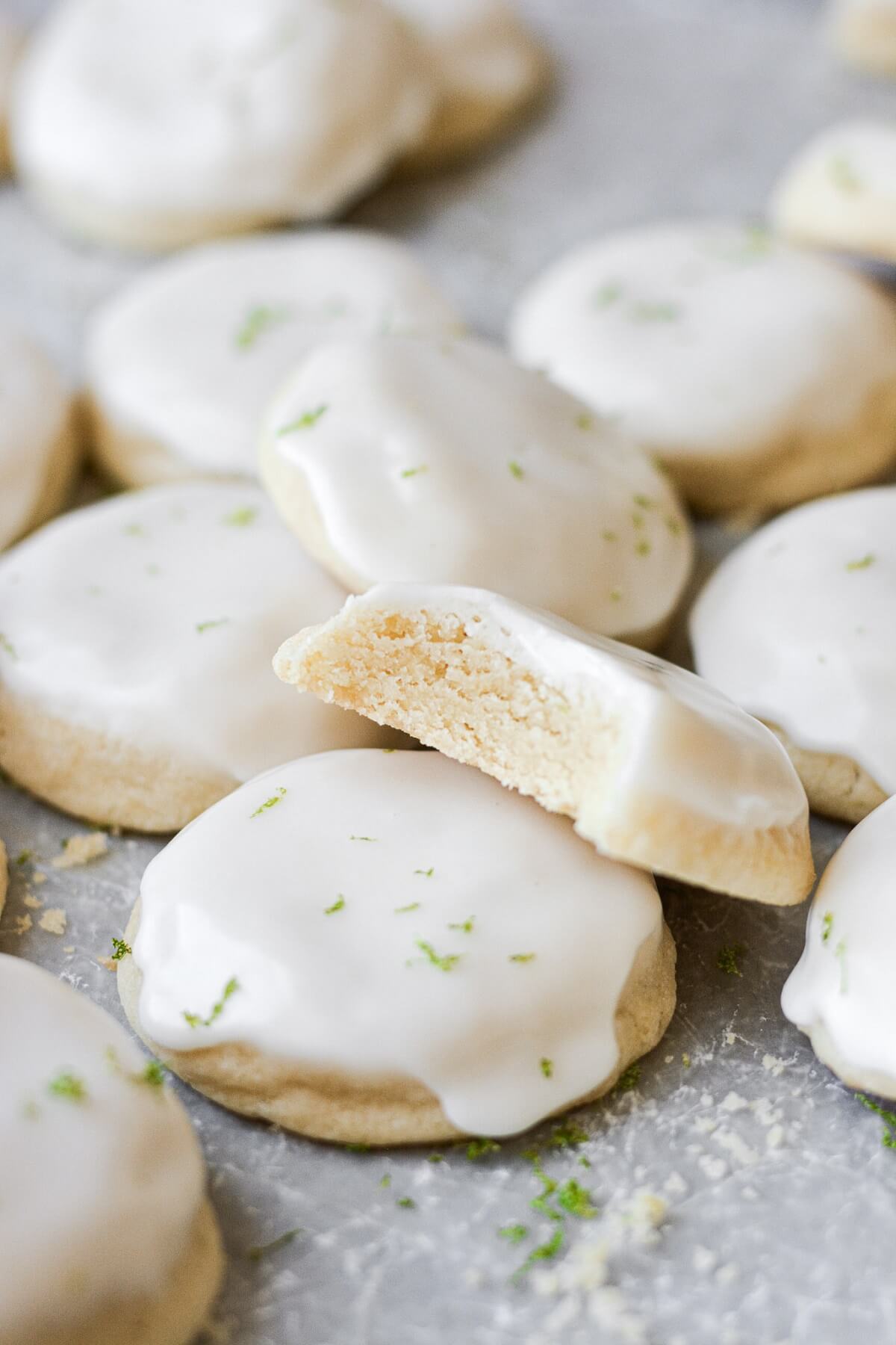Iced lime sugar cookies, one with a bite taken.