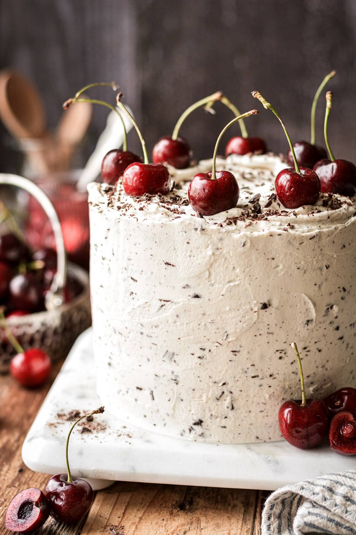 White forest cake with fresh cherries and chocolate chip whipped cream frosting.