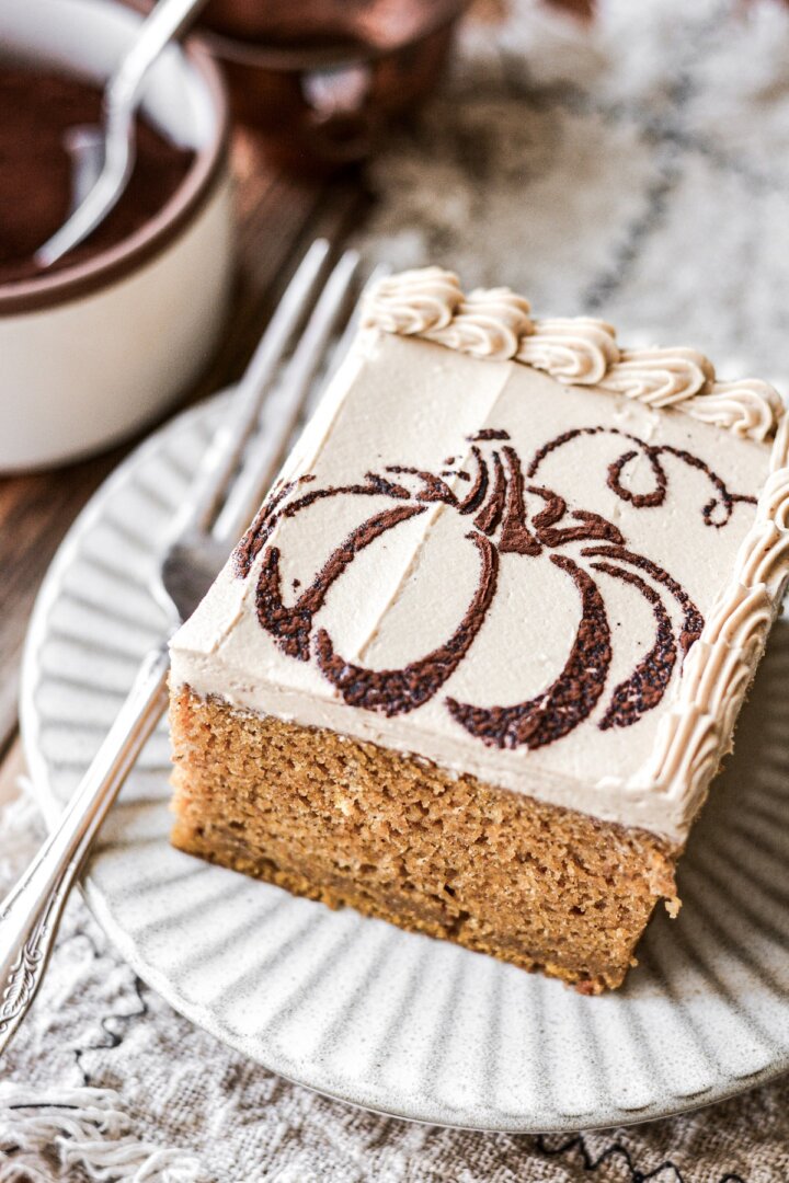 A piece of pumpkin cake with coffee buttercream and a pumpkin stencil on top.