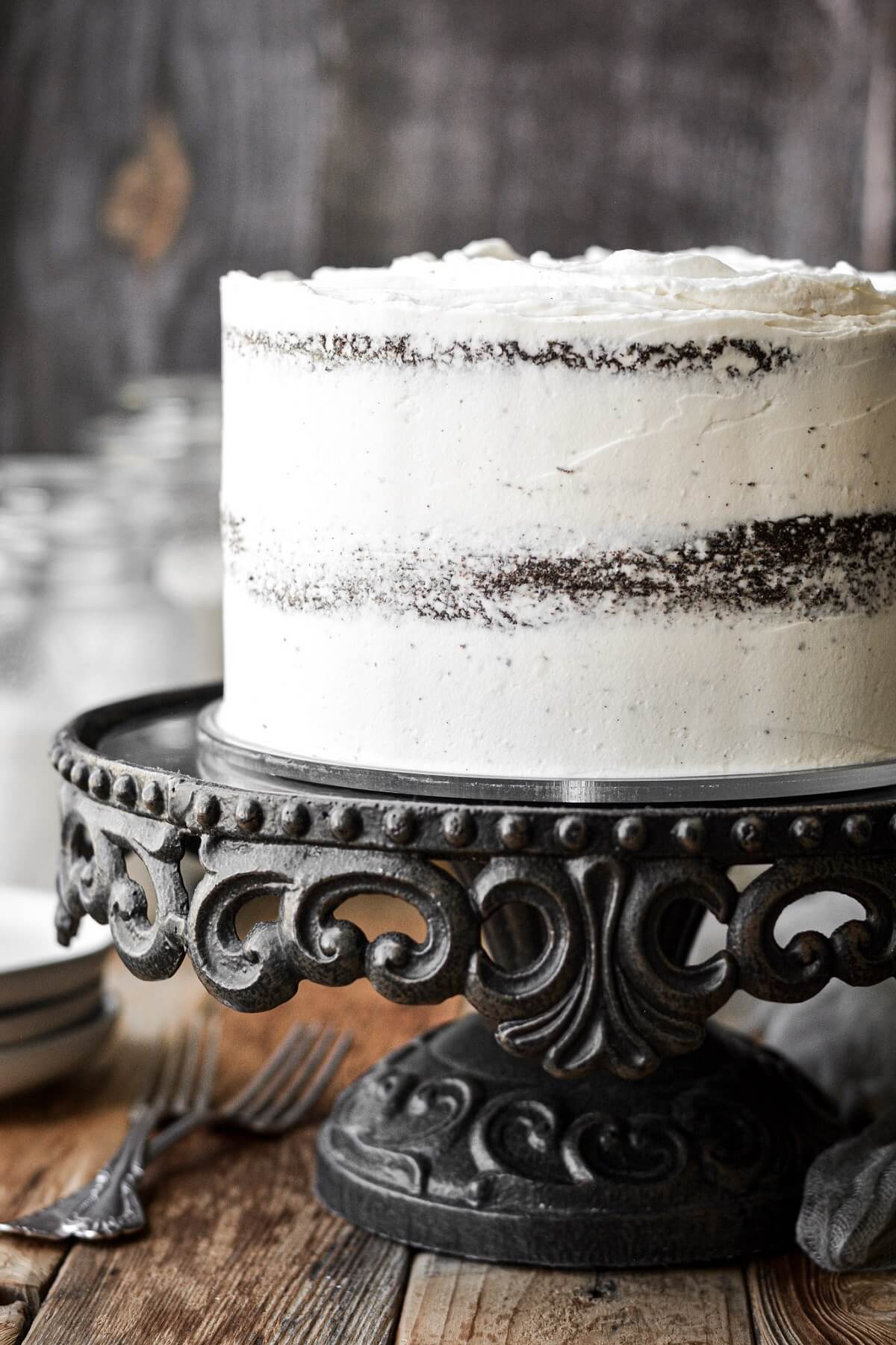 Chocolate mayonnaise cake with vanilla buttercream on a black cake stand.