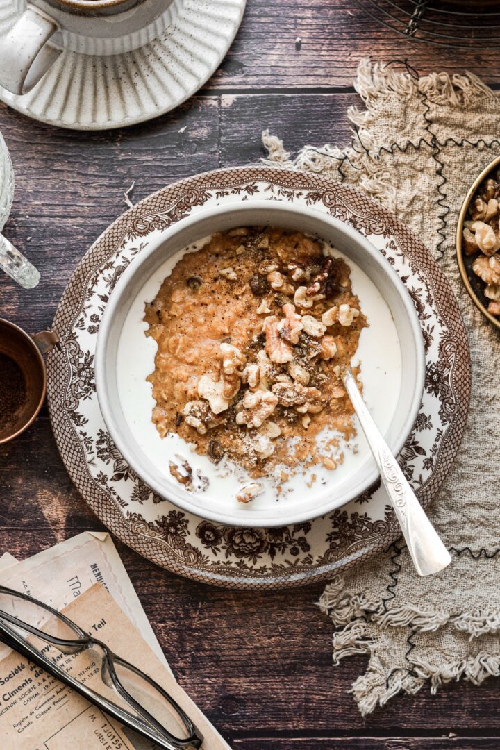 Maple pumpkin oatmeal in a bowl with milk, walnuts and raisins.
