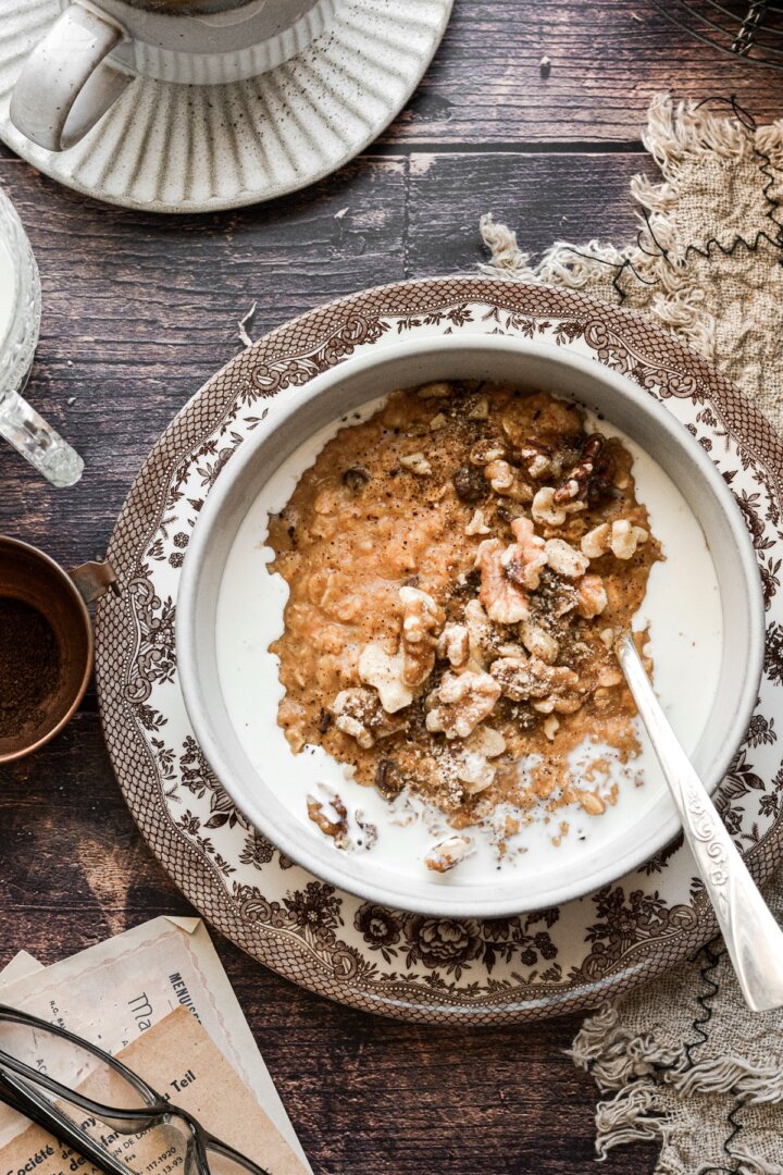 Maple pumpkin oatmeal in a bowl with milk, walnuts and raisins.