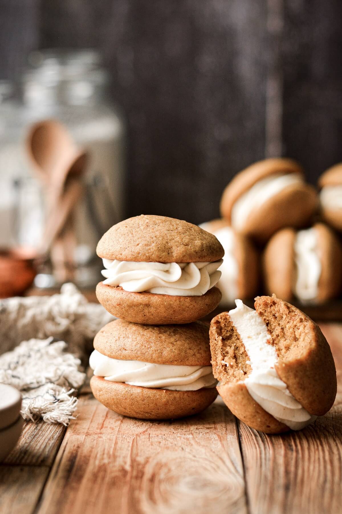 Stack of pumpkin whoopie pies, one with a bite taken.