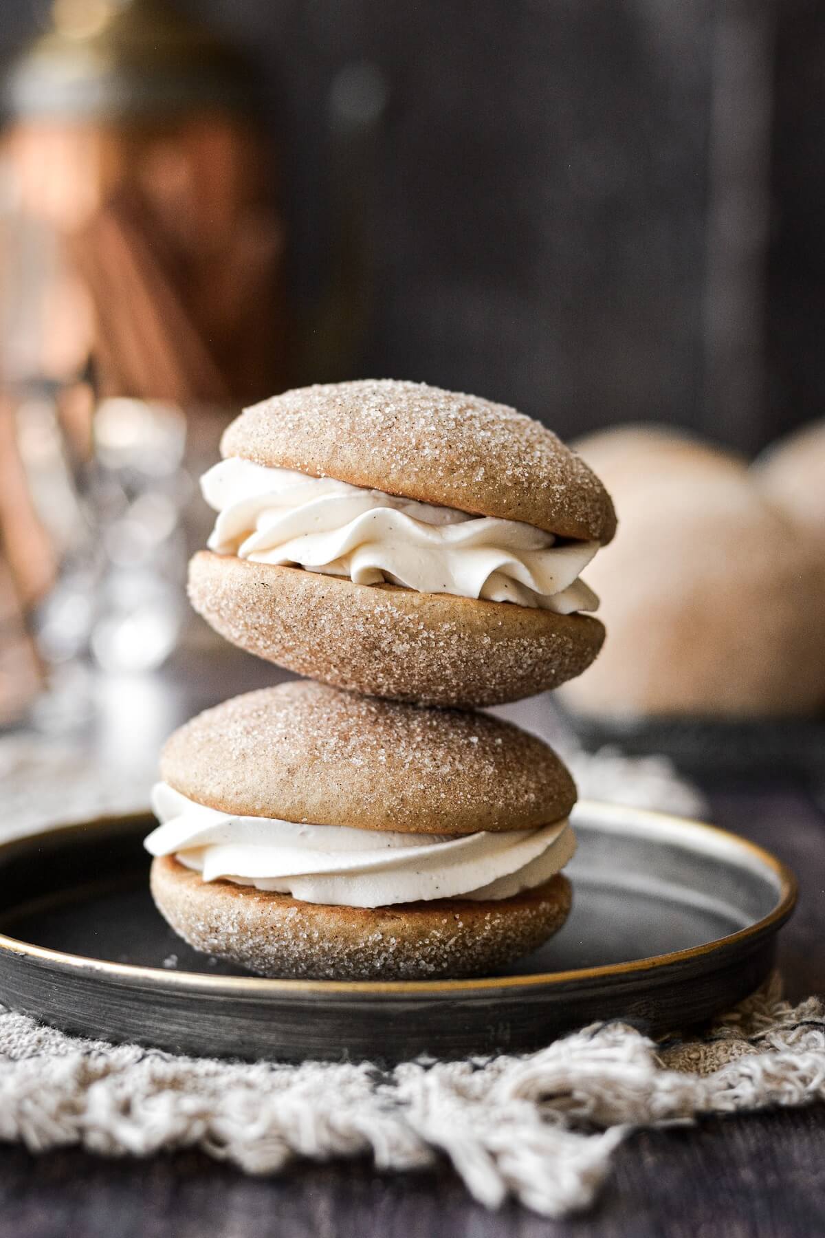 Two snickerdoodle whoopie pies stacked on a black plate.