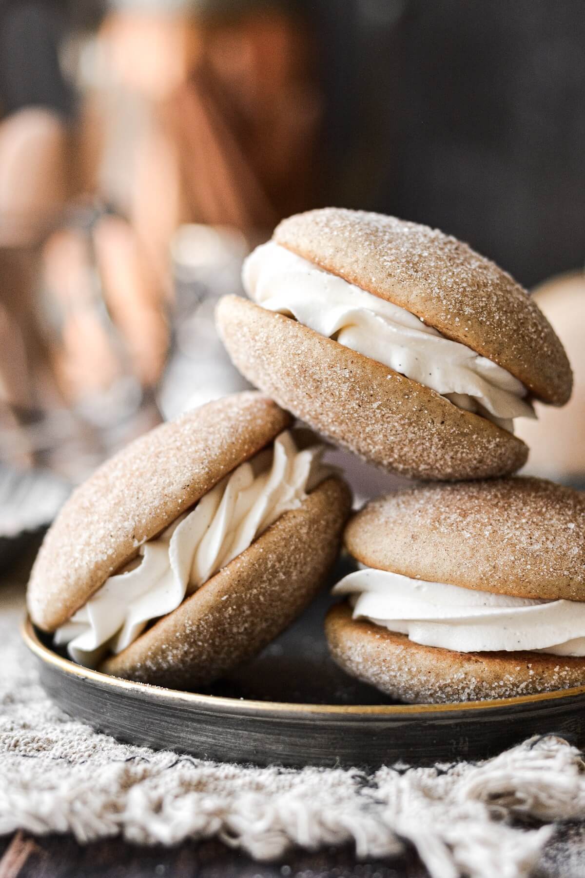 Snickerdoodle whoopie pies stacked on a black plate.