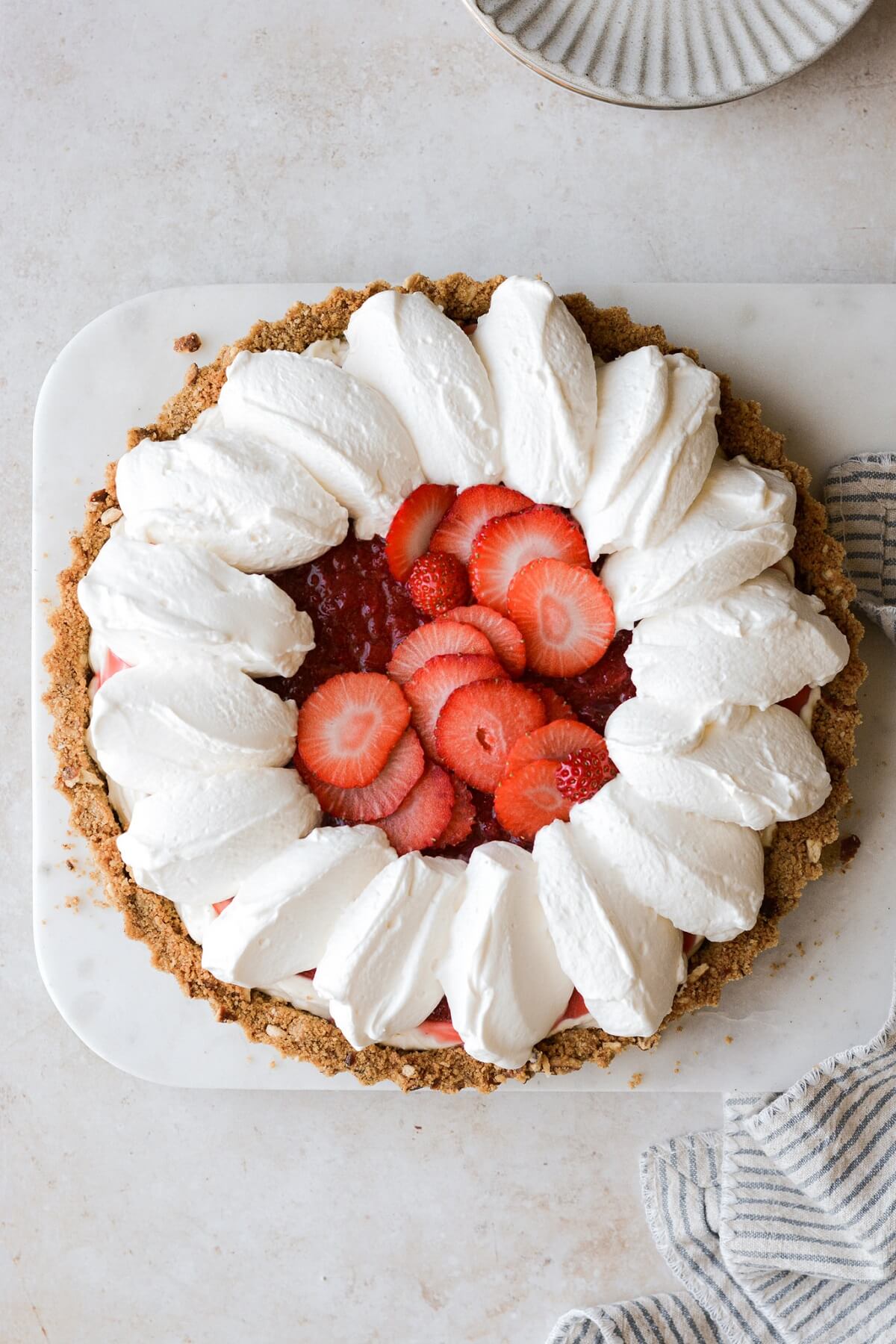 Strawberry cream cheese pretzel pie with whipped cream and sliced strawberries.