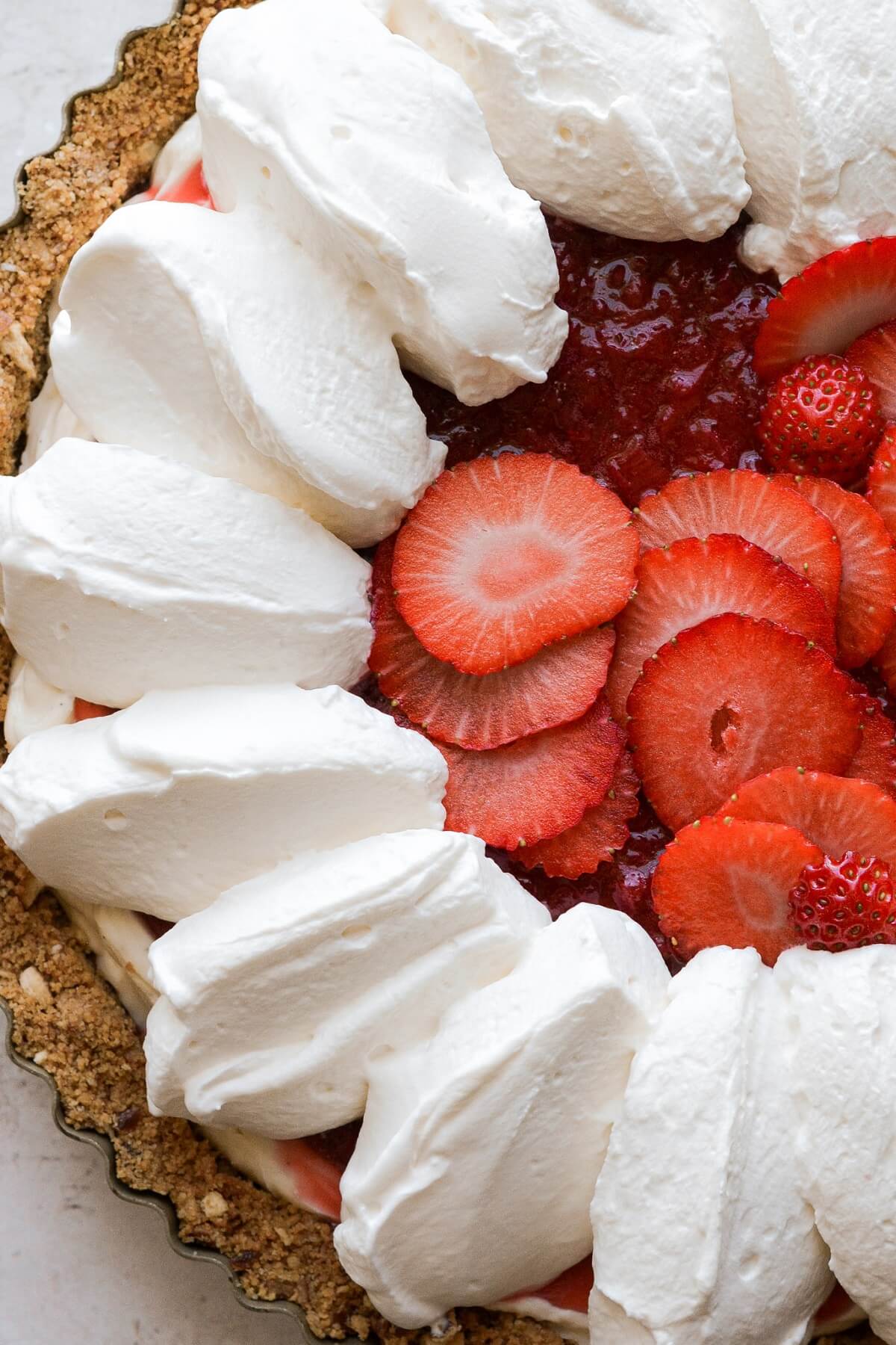 Whipped cream and sliced strawberries on pie.