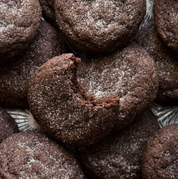 Chocolate snickerdoodles, one with a bite taken.
