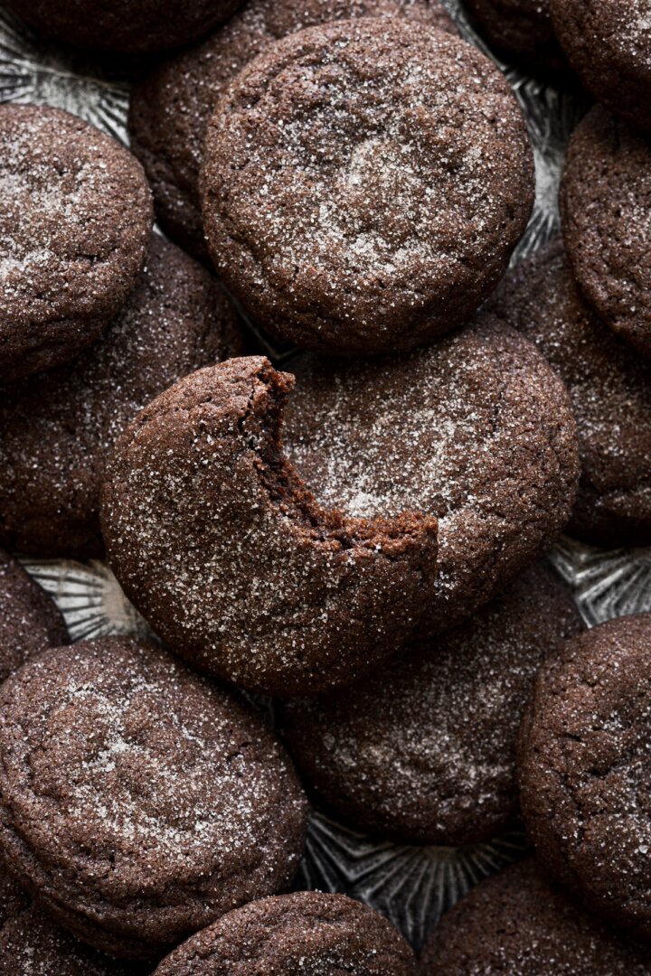 Chocolate snickerdoodles, one with a bite taken.