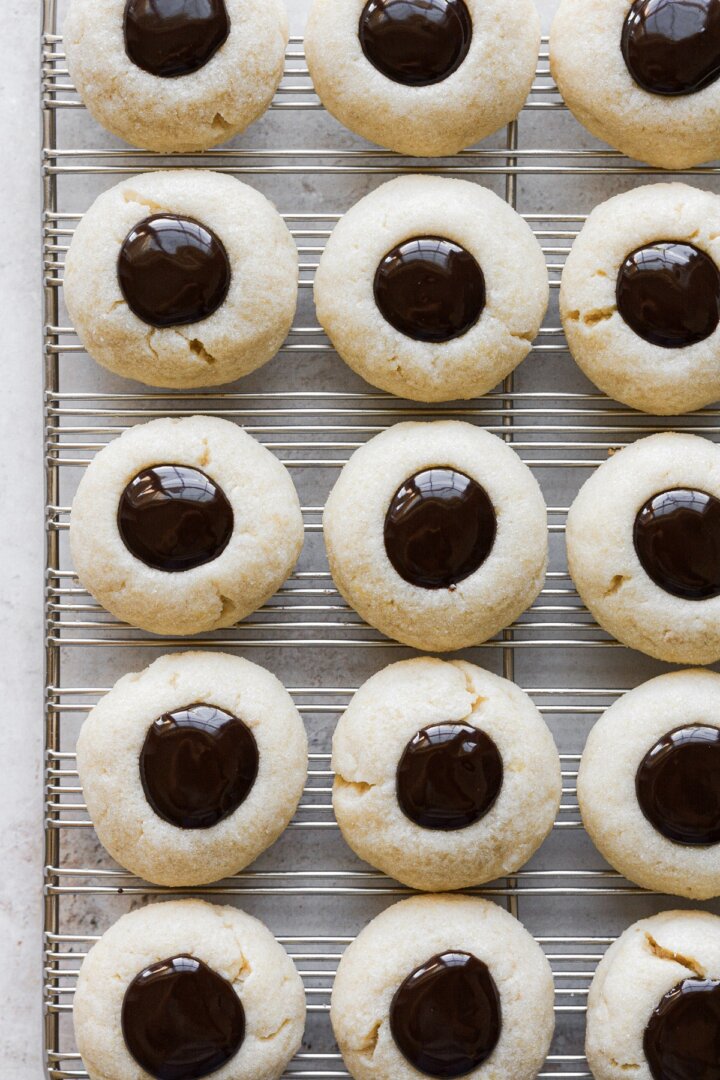 Chocolate thumbprint cookies on a cooling rack.