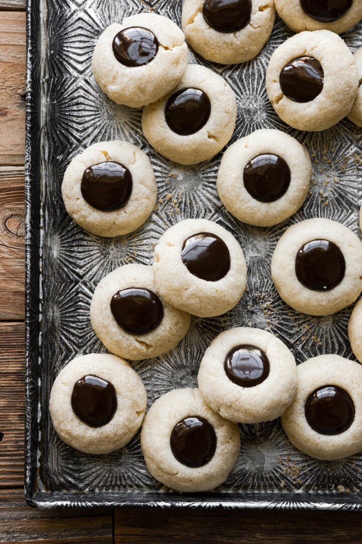 Chocolate thumbprint cookies on a baking sheet.