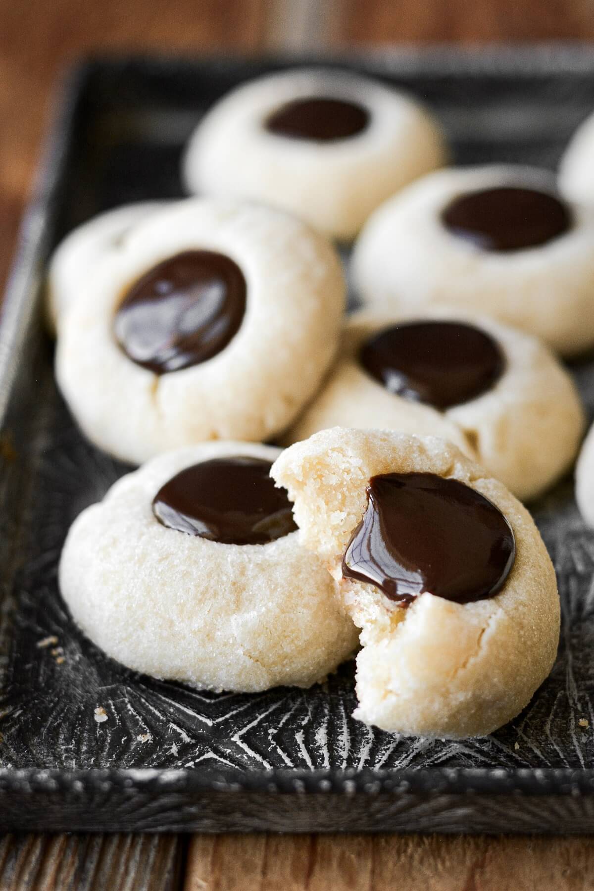 Chocolate thumbprint cookies, one with a bite taken.