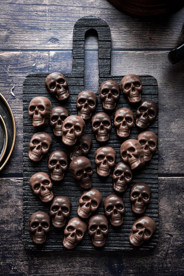 Mini chocolate skulls on a cutting board.