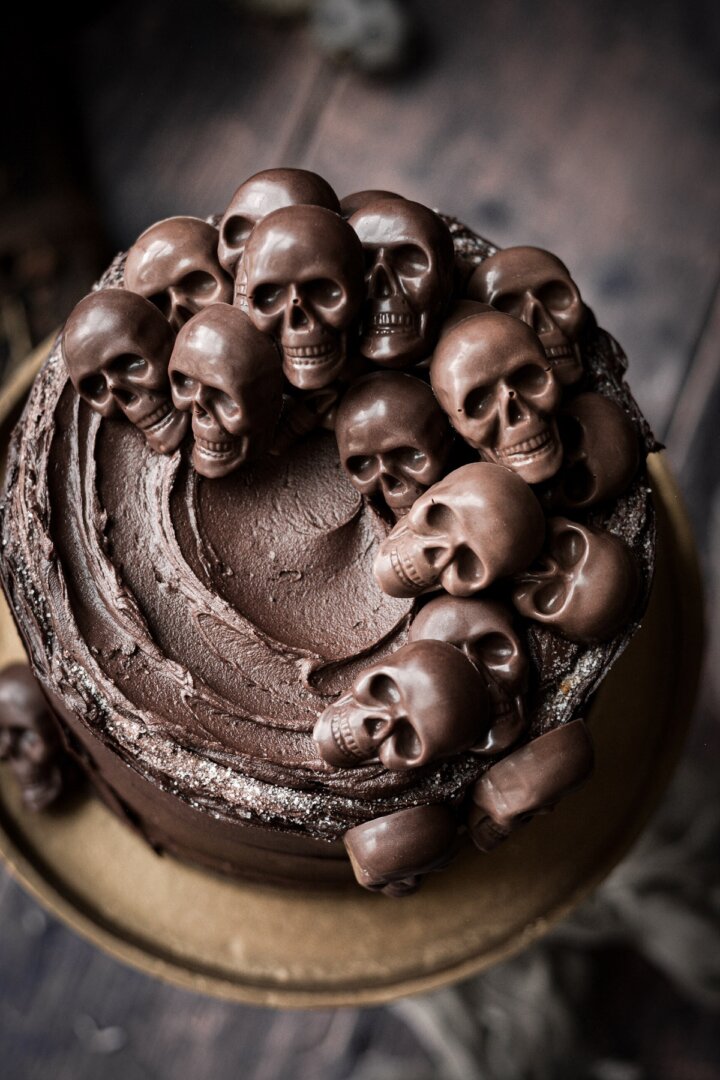 Mini chocolate skulls on a chocolate frosted cake.