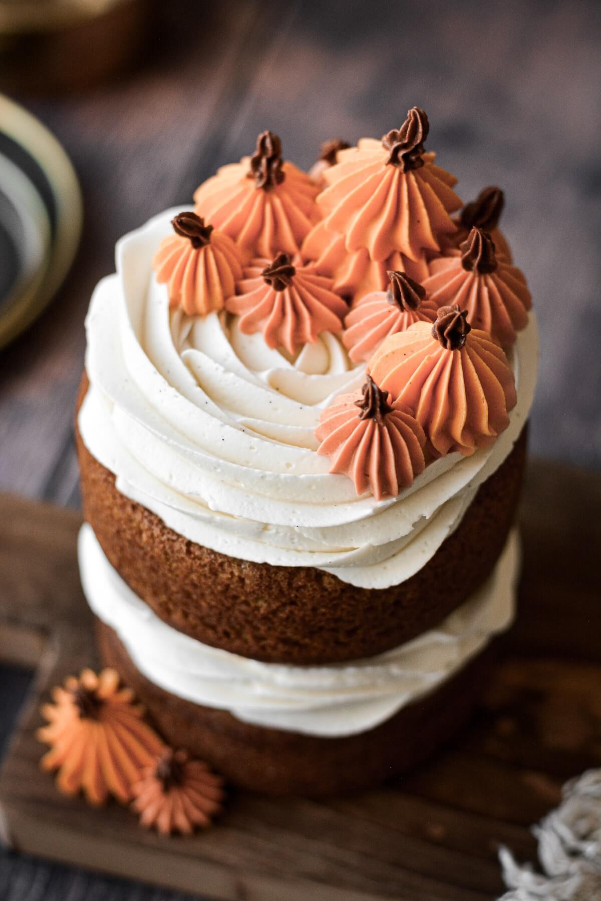 A naked mini pumpkin cake with vanilla buttercream and orange piped pumpkins.