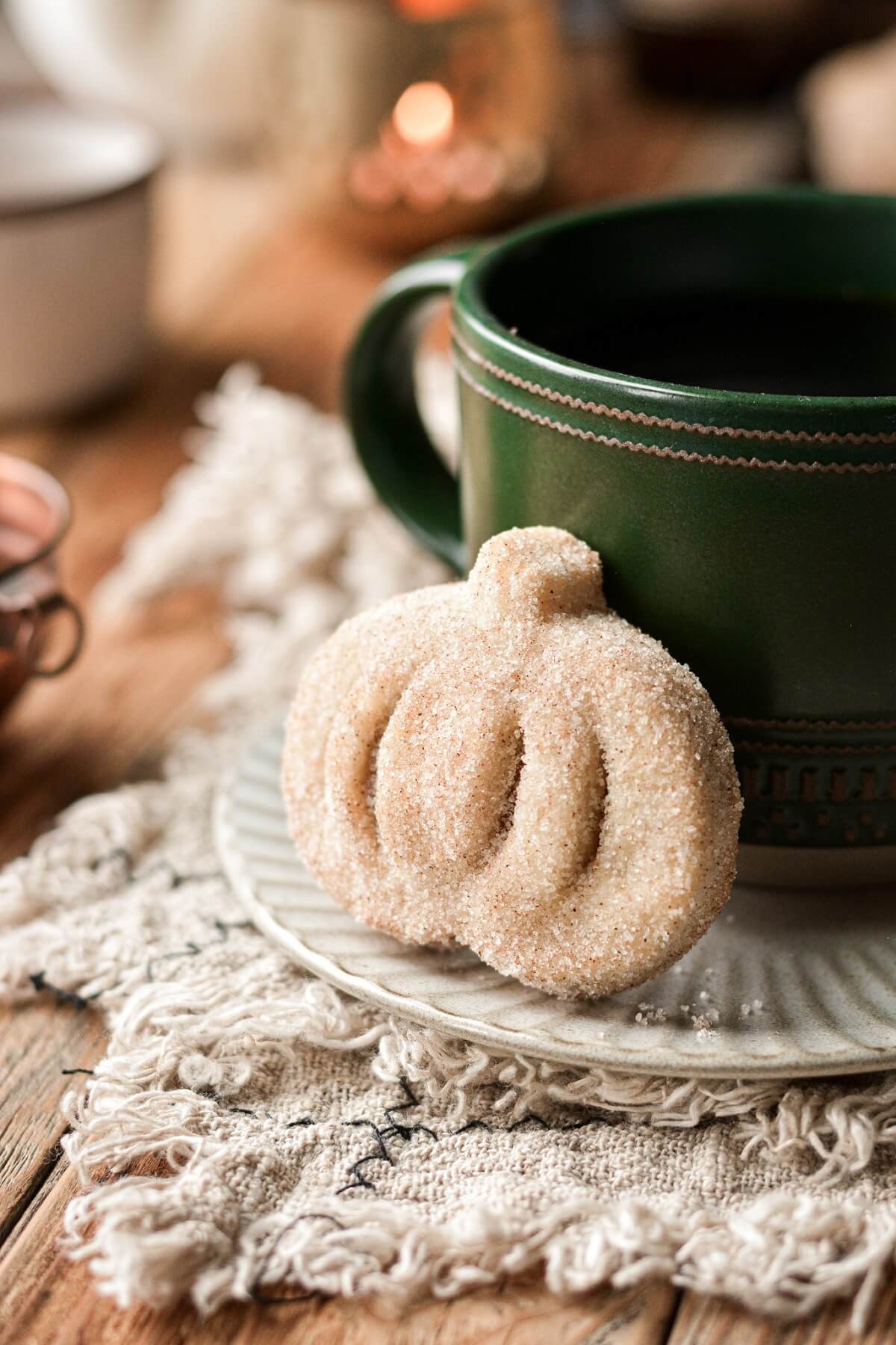 Cinnamon sugar coated mini pumpkin pie leaning against a coffee cup.