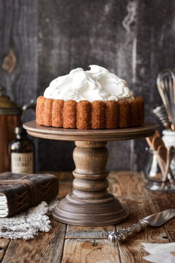 Pumpkin Charlotte cake with whipped cream on a wooden cake stand.