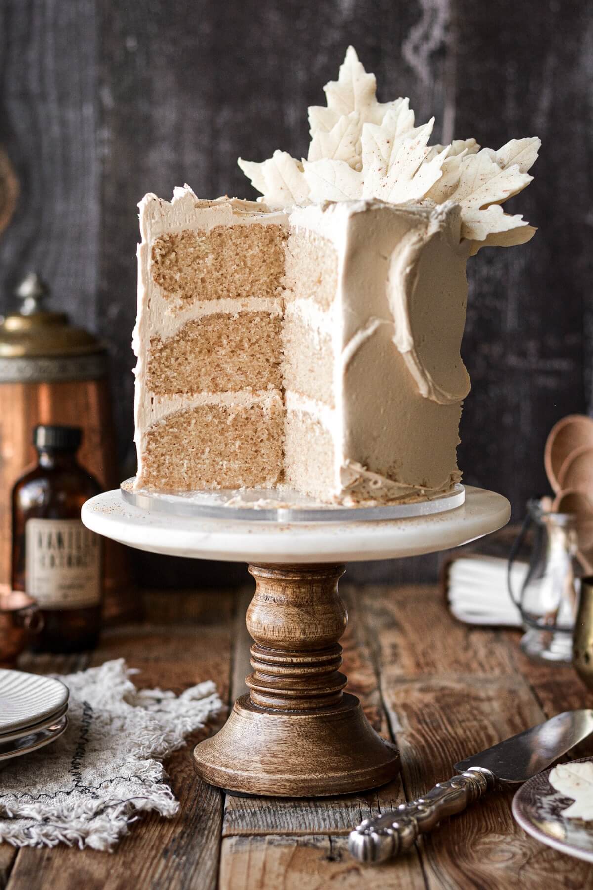 White chocolate maple spice cake with white chocolate leaves, with a slice cut.