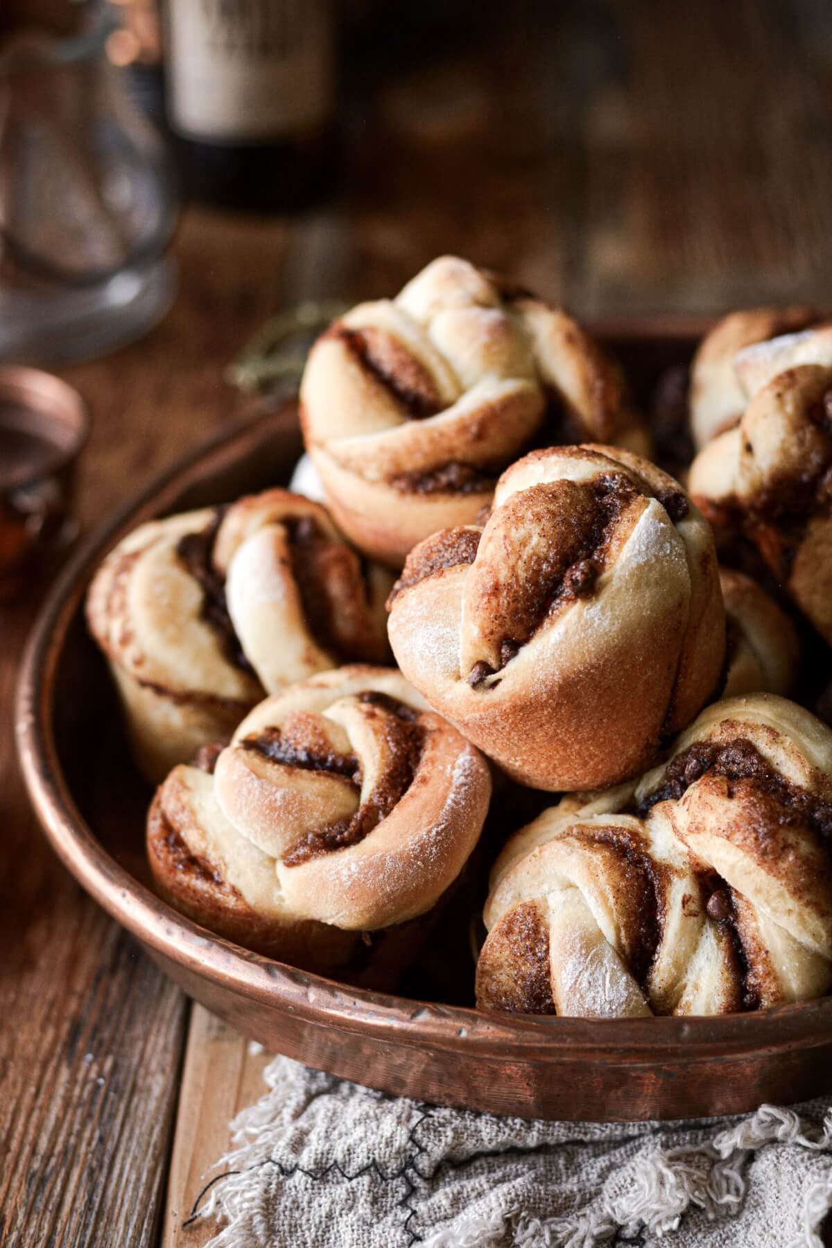 Chocolate cinnamon roll knots piled in a copper dish.