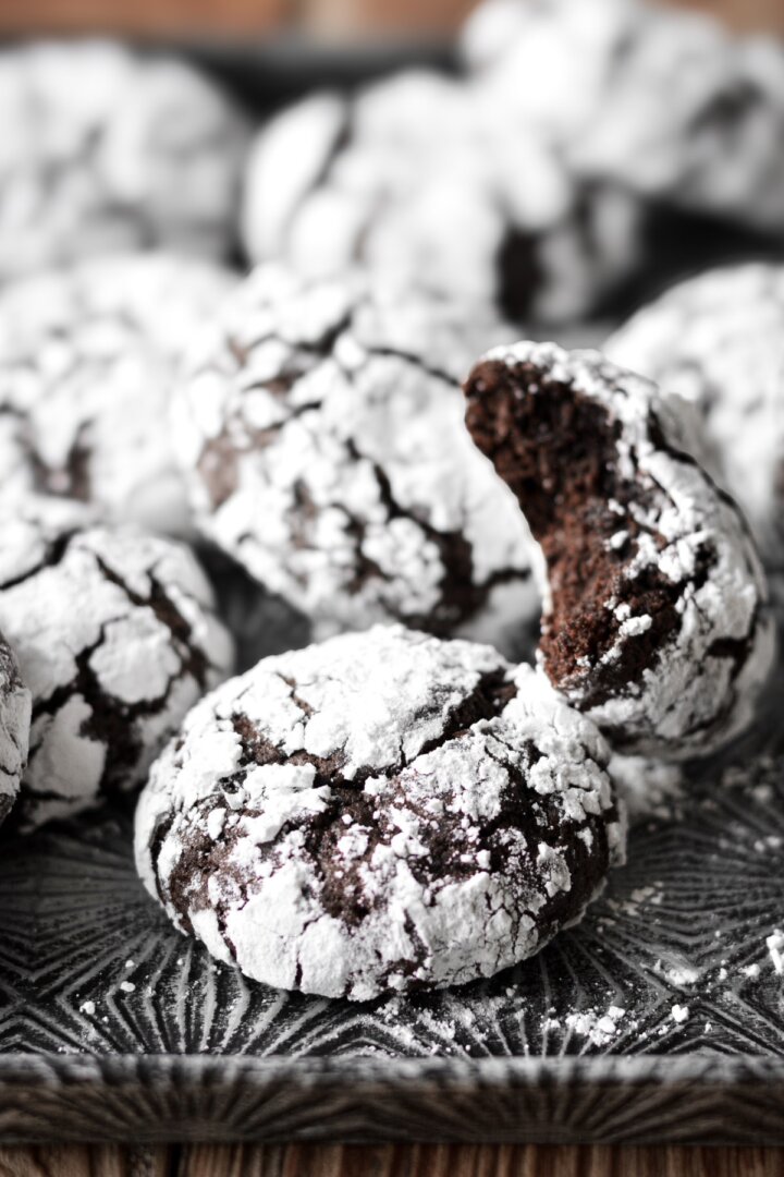 Chocolate crinkle cookies, one with a bite taken.