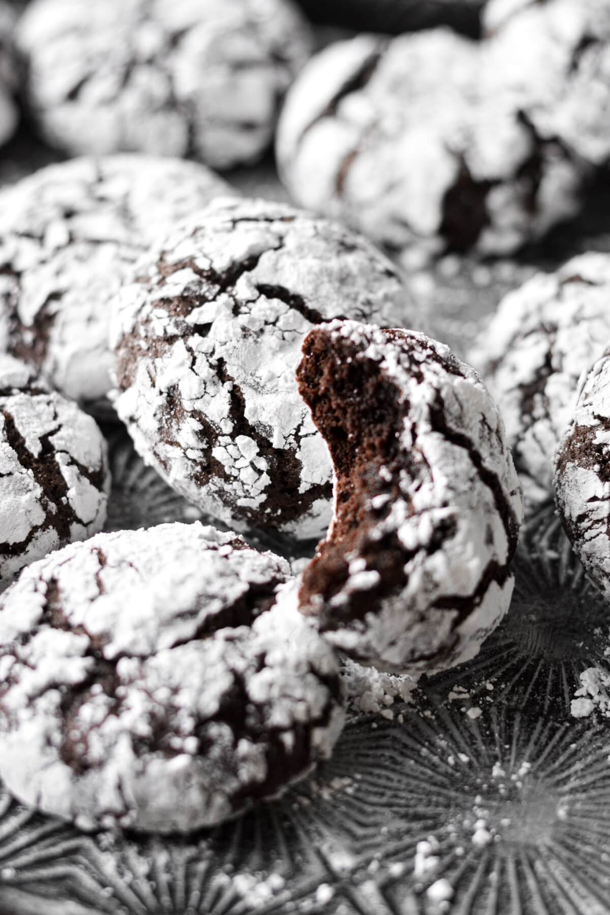 Chocolate crinkle cookies, one with a bite taken.
