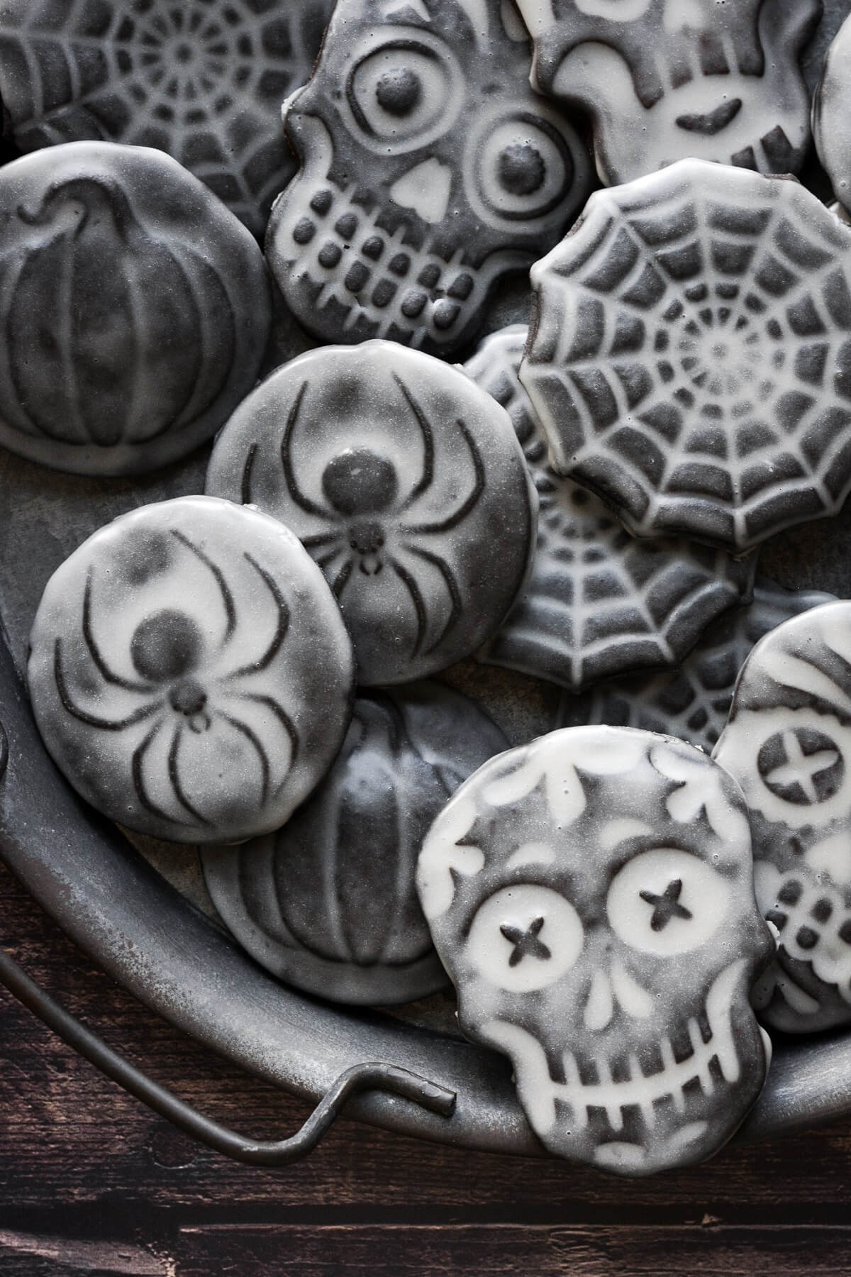 Stamped chocolate Halloween cookies with vanilla icing, in spiders, skulls, and spiderwebs.