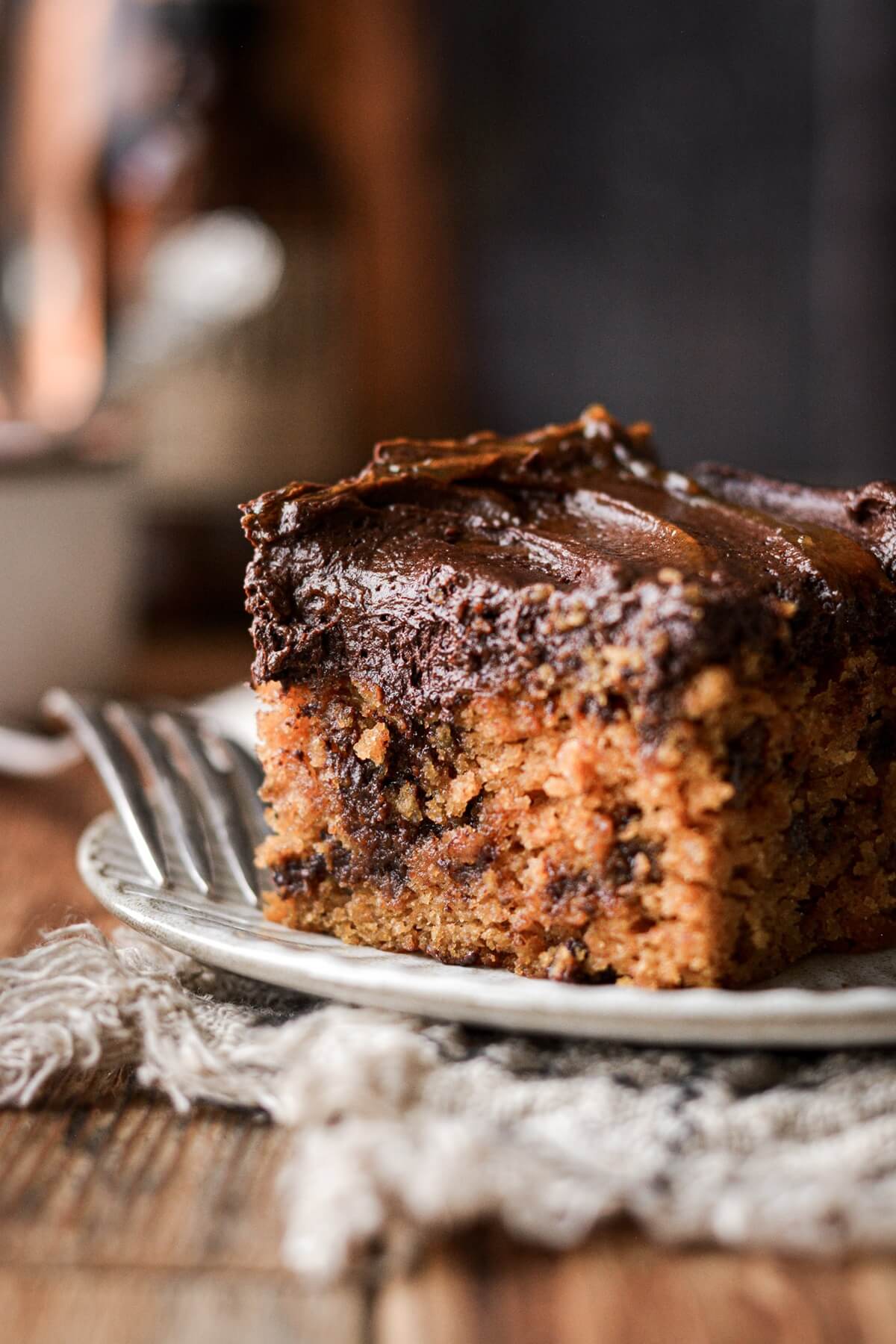 A piece of pumpkin chocolate chip cake with chocolate frosting.