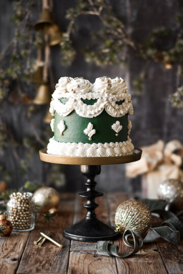 Green and white Lambeth cake, surrounded by gold Christmas ornaments.