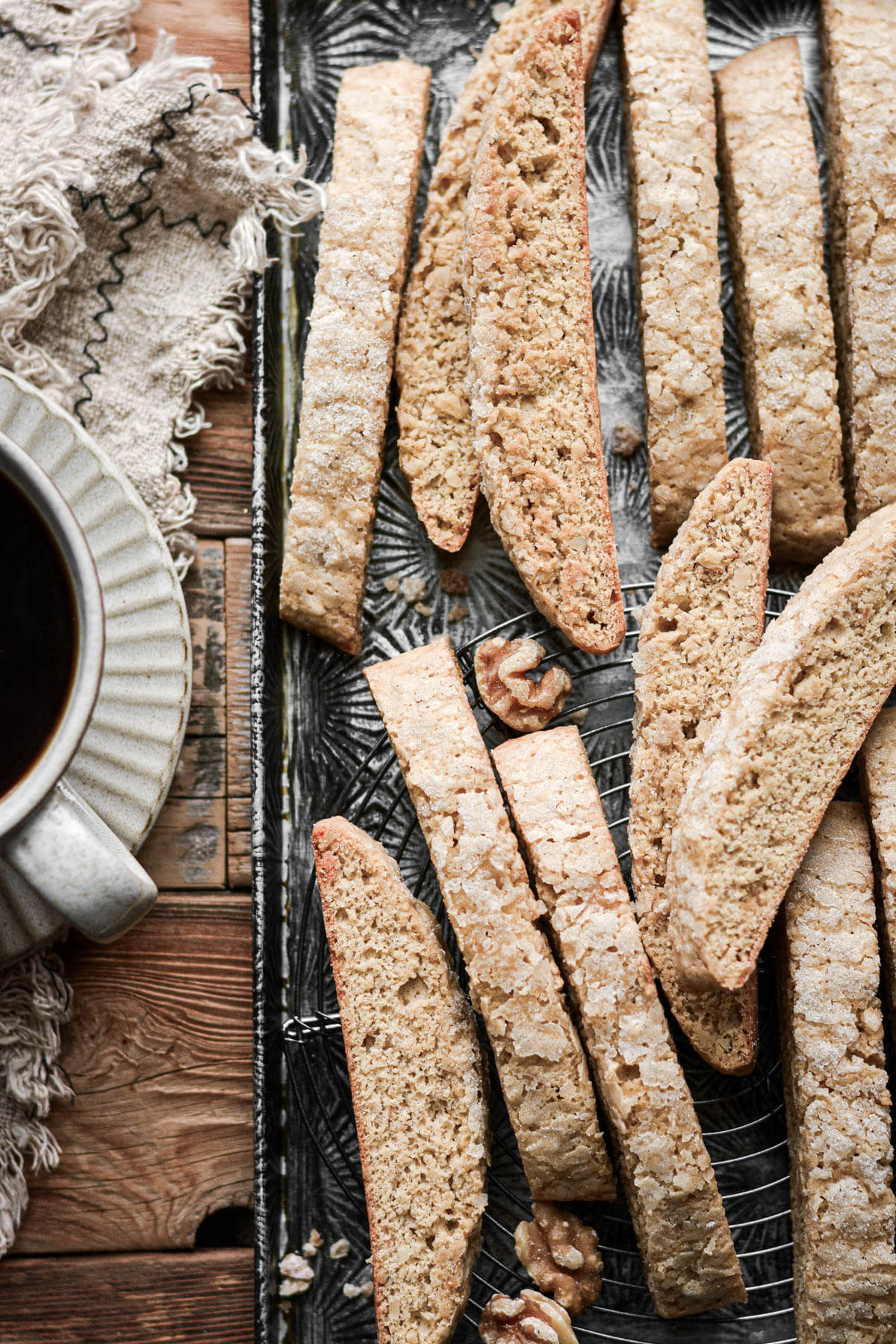 Ginger walnut biscotti next to a cup of coffee.