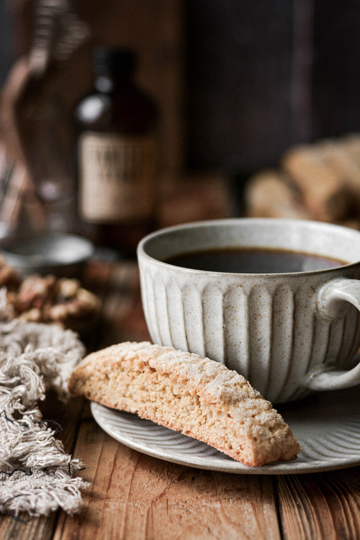 Ginger walnut biscotti resting next to a cup of coffee.