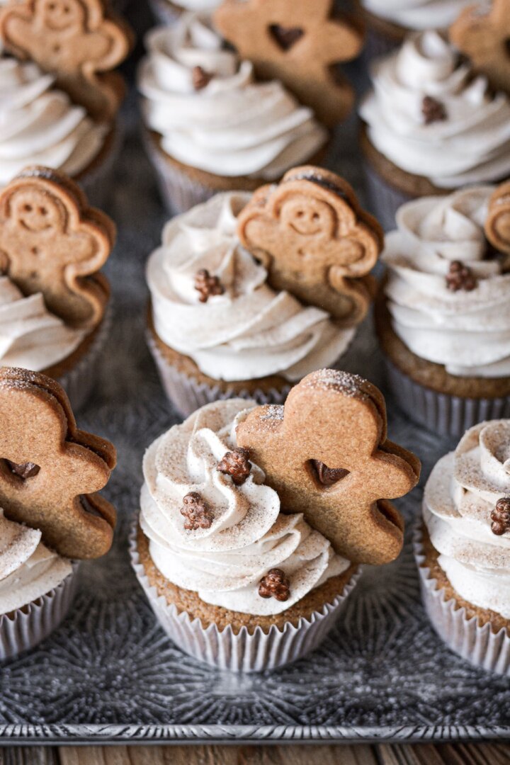 Gingerbread cupcakes with gingerbread cookies on a baking sheet.