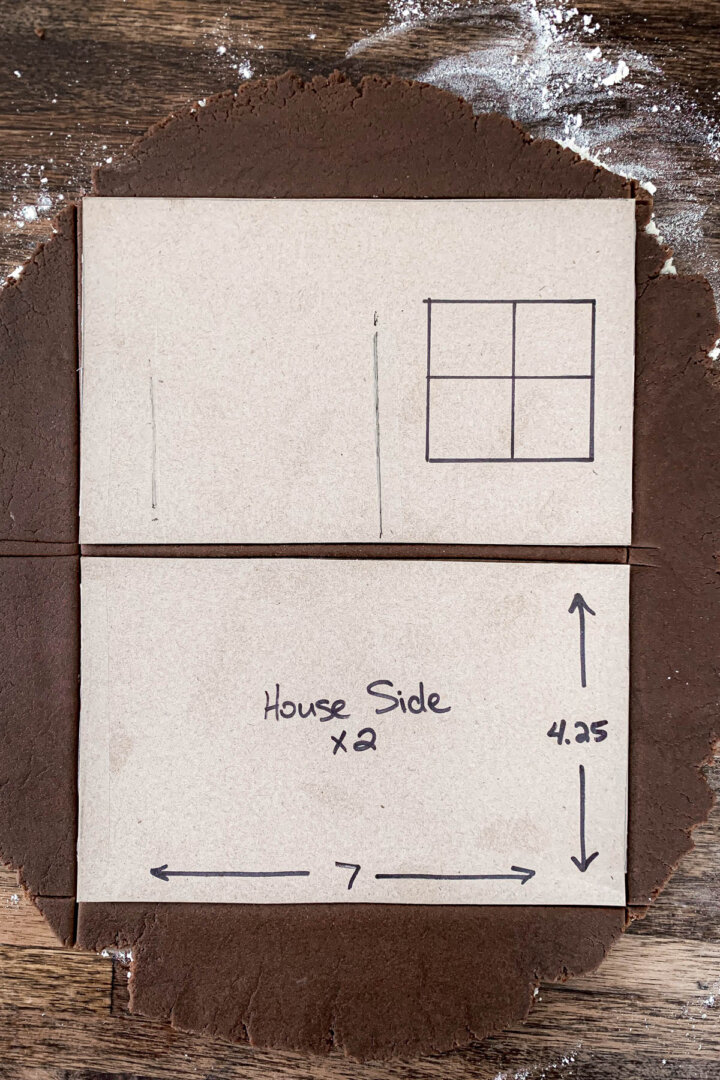 Gingerbread dough rolled out, with a cardboard house template.