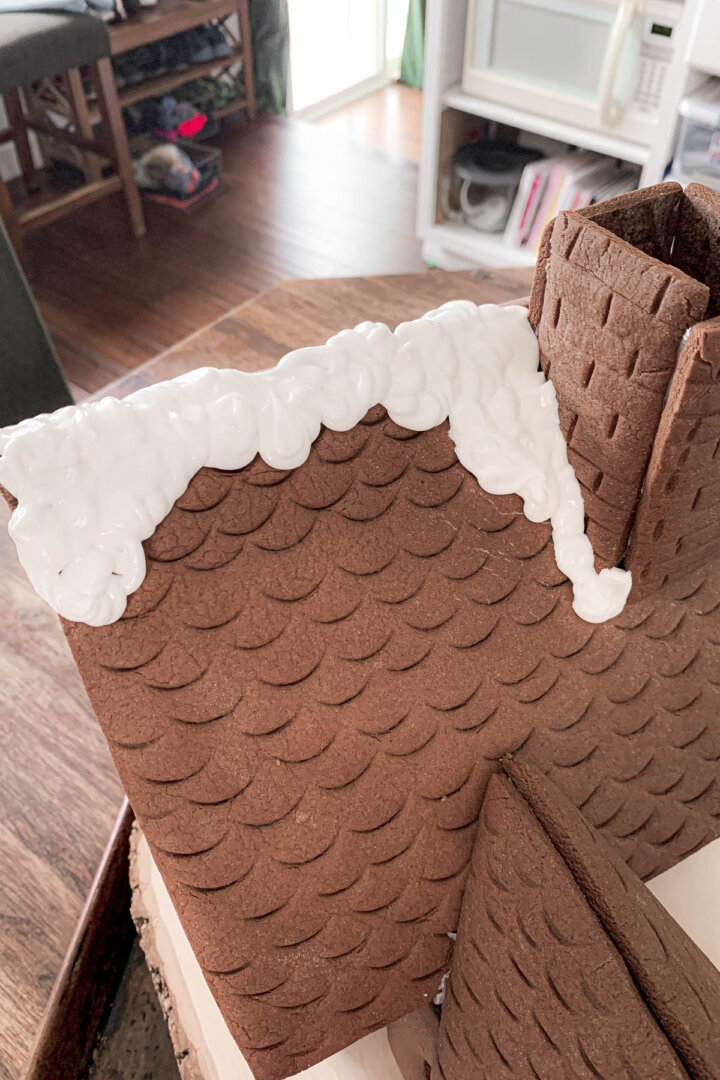 Step 2 for decorating a gingerbread house with royal icing snow.