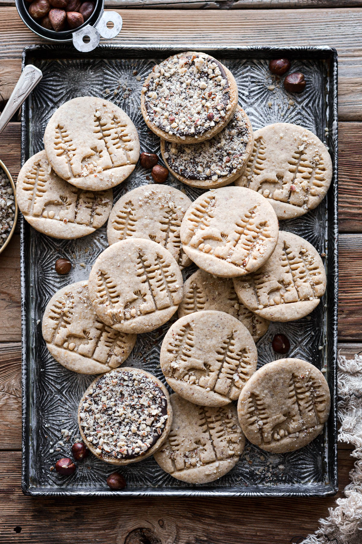 Hazelnut cookies with a trees and moose design, arranged on a baking sheet.
