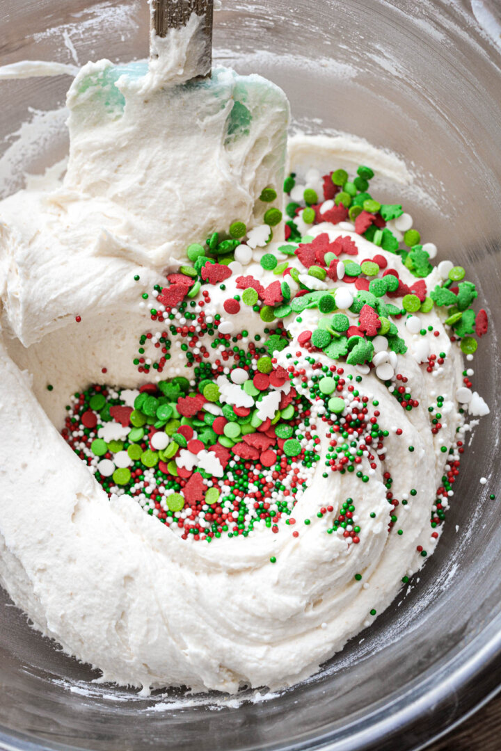 Christmas sprinkles scattered over a bowl of brown butter frosting.