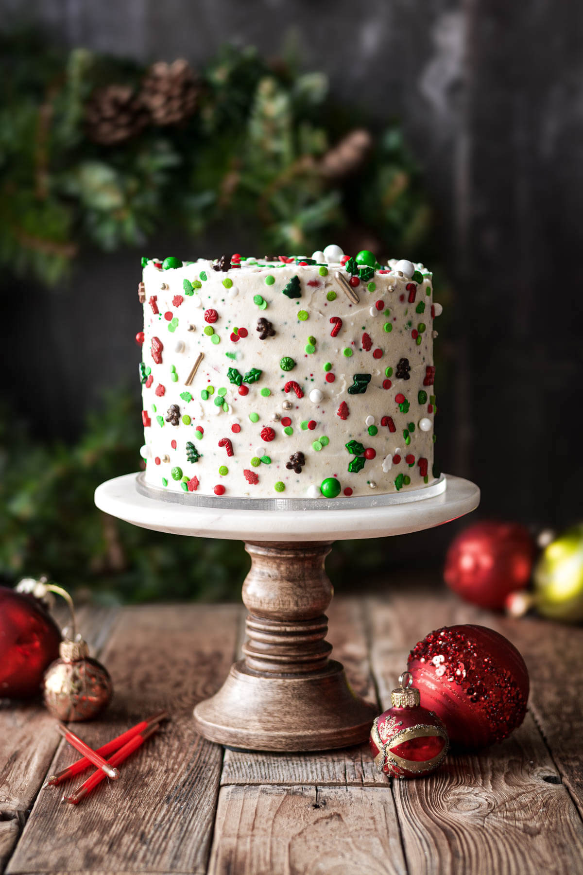 Christmas sprinkle cake on a marble and wood cake stand.