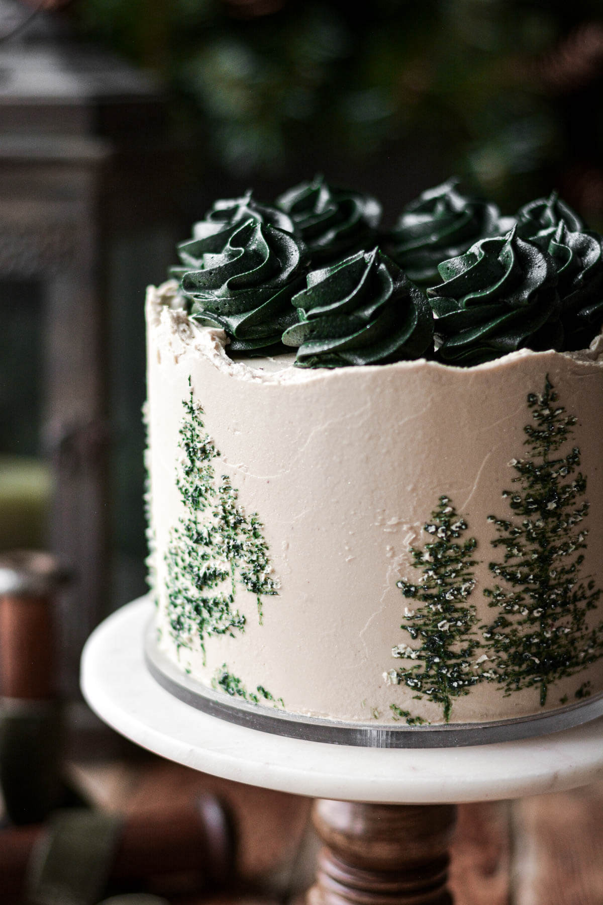 Green evergreen trees painted onto the side of a cake.