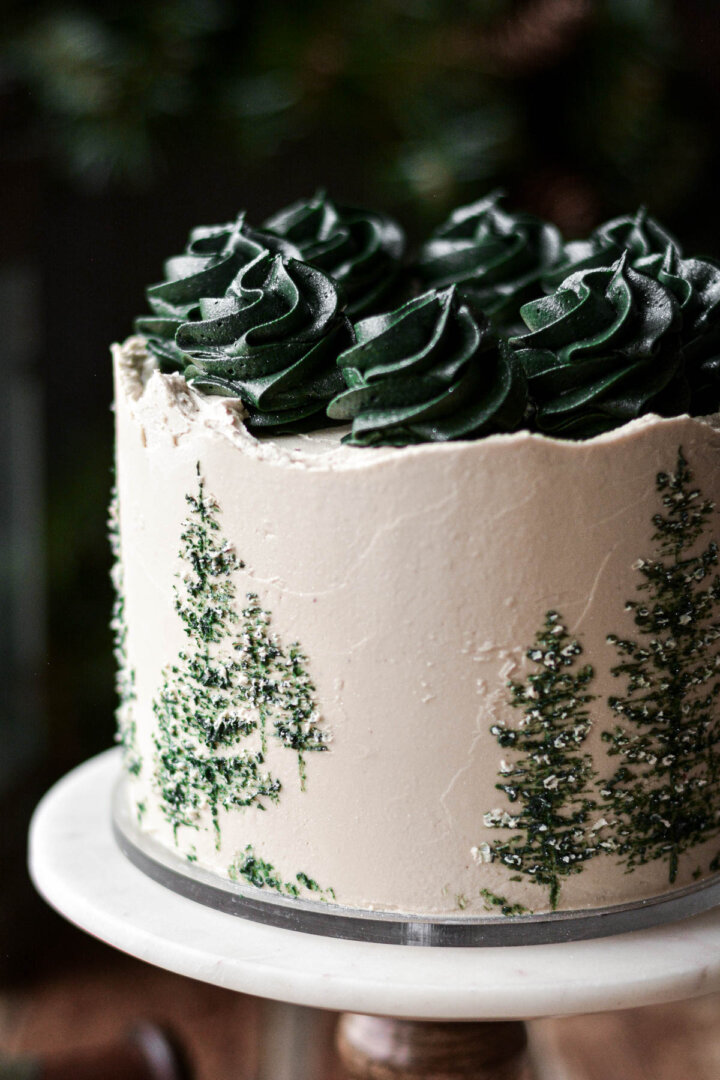 Green evergreen trees painted onto the side of a cake.