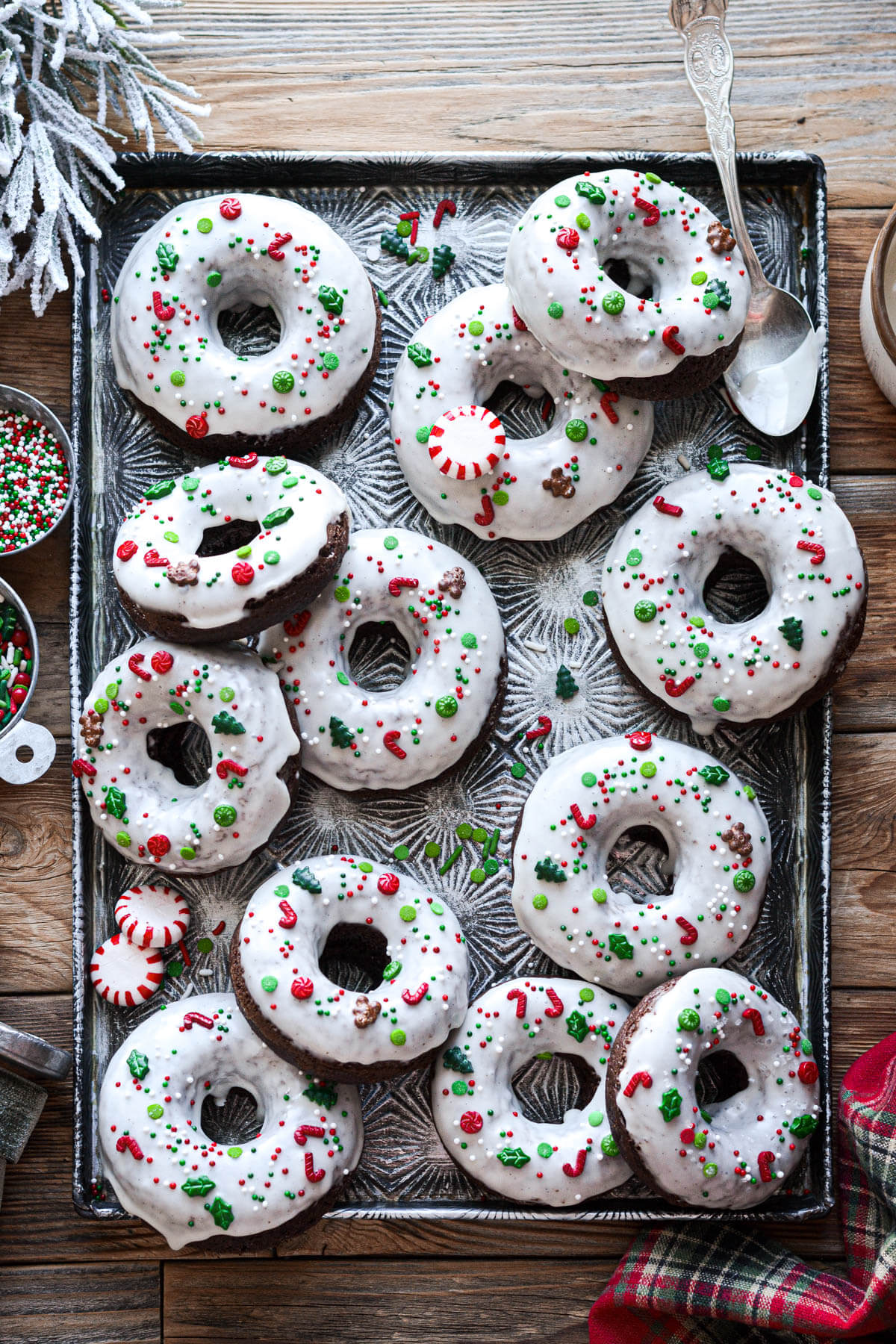 Chocolate peppermint donuts with Christmas sprinkles on a vintage baking sheet.