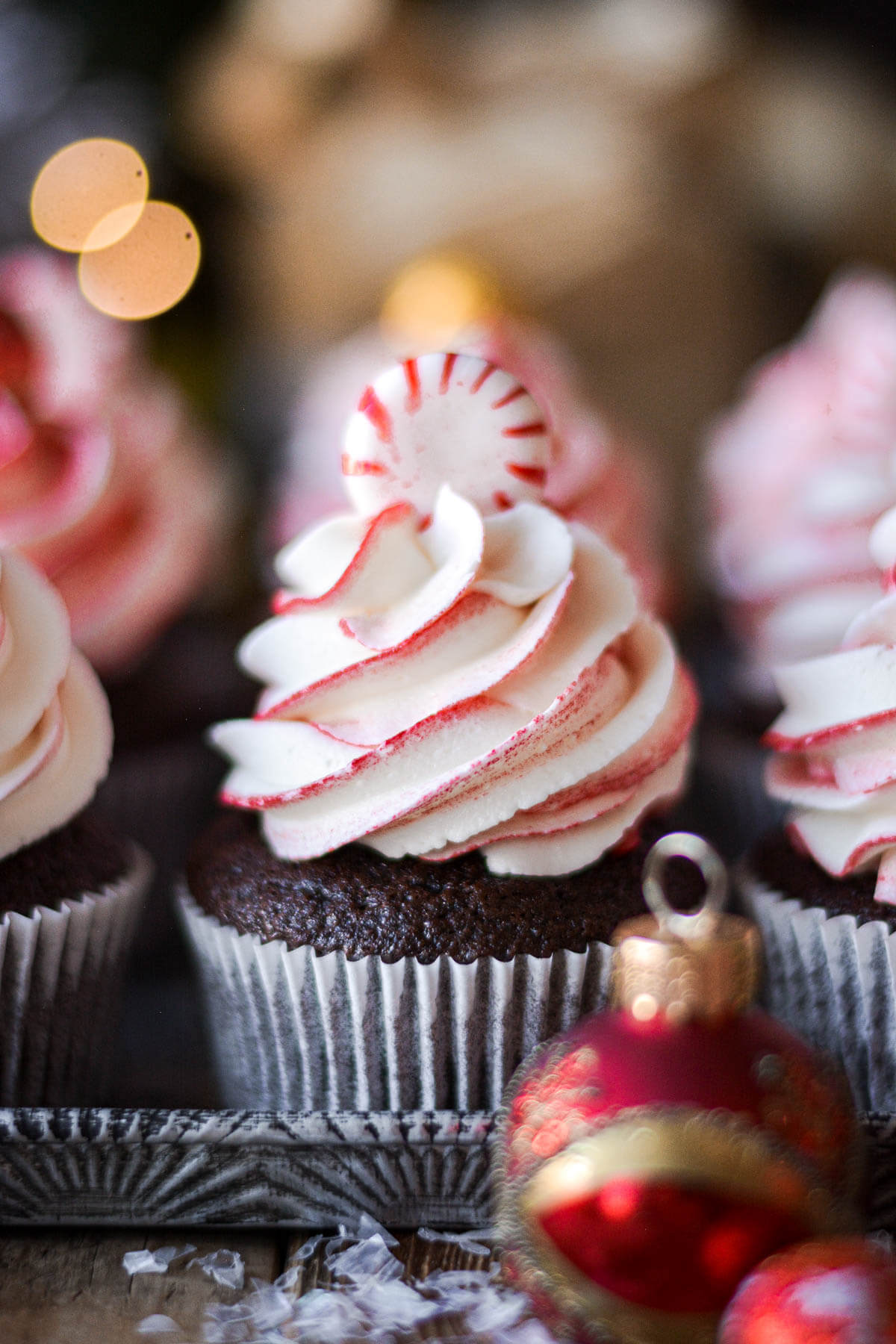 Red and white swirled peppermint buttercream on a chocolate cupcake, topped with a peppermint candy.